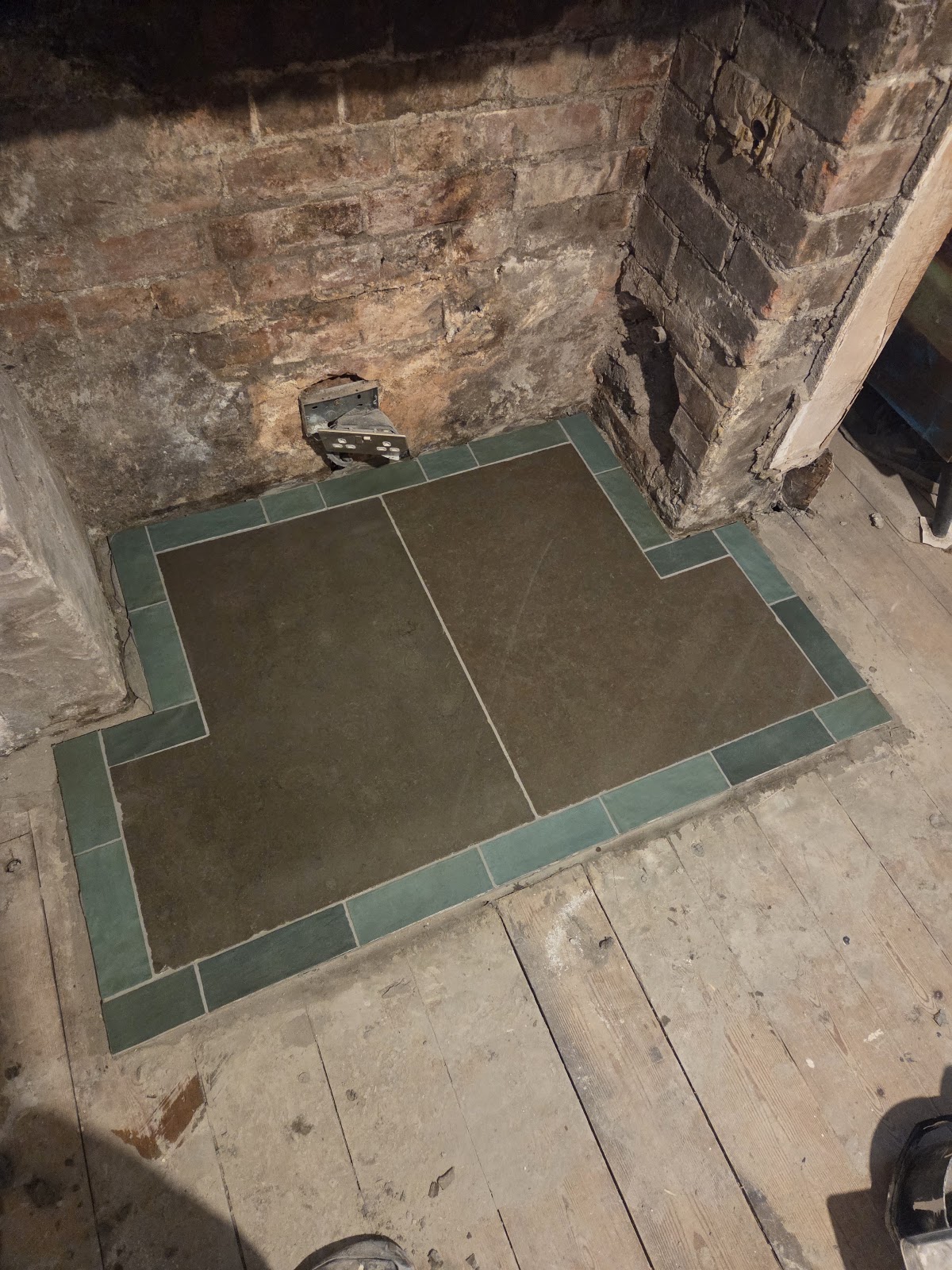 Fireplace hearth tiled with a green border by Vanta Tiling